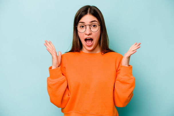 Young caucasian woman isolated on blue background celebrating a victory or success, he is surprised and shocked. - Photo, Image