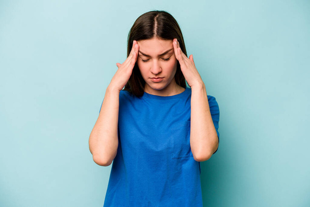 Young caucasian woman isolated on blue background touching temples and having headache. - Photo, image