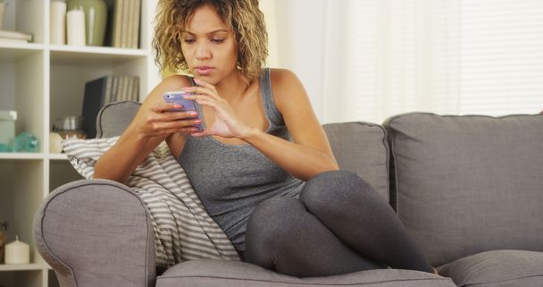 Fekete nő használ smartphone kanapén - Fotó, kép