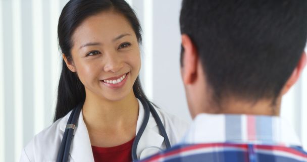 Azjatycki lekarz mówi do pacjenta - Zdjęcie, obraz