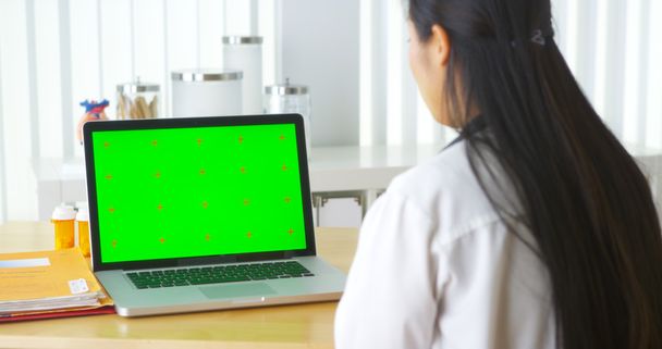 緑色の画面でノート パソコンに話している中国の医師 - 写真・画像