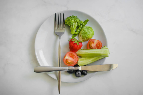 Vegetables and fruits on a plate on a light background - Photo, Image