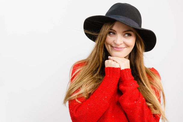 Female autumnal fashion. Woman wearing red sweater black stylish hat, smiling and posing in studio - Foto, afbeelding