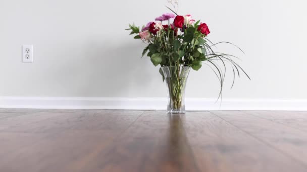Parallax effect door te bewegen in de voorkant van een vaas met bloemen op gelamineerde vloer van een lege kamer met witte muur - Video