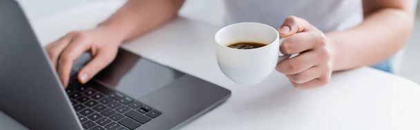 コーヒーカップを持った女性がノートパソコンやバナーを使って - 写真・画像