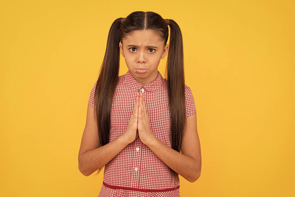 Unhappy girl prayer plead holding palms together in prayer gesture yellow background, pleading - Photo, Image