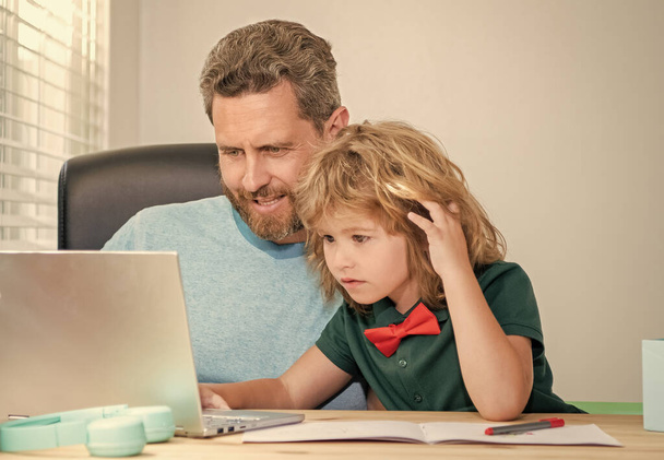 glücklich aufmerksamer Vater und Sohn in der Schule arbeiten online am Laptop, Videokonferenz - Foto, Bild