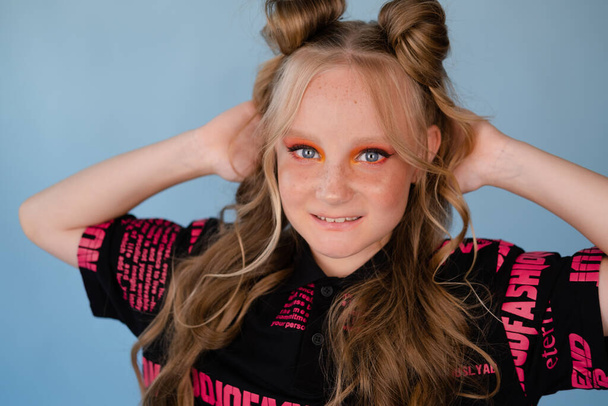 módní portrét teenagera. tween školní dívka s oranžovým make-up na sobě růžové stylové cool oblečení na modrém pozadí. - Fotografie, Obrázek