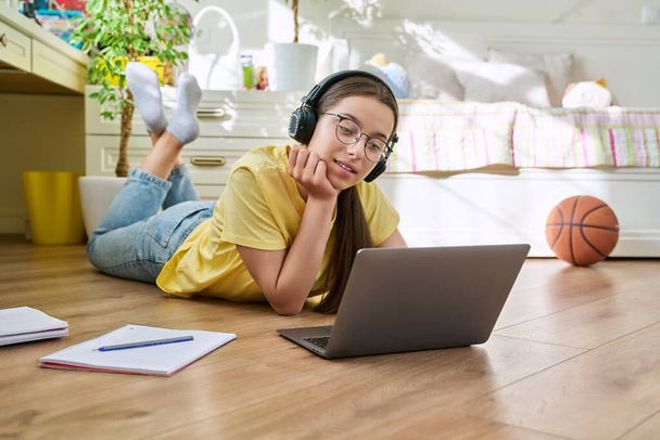 十代の女の子とともに眼鏡をかけて家で勉強ラップトップを使用して - 写真・画像