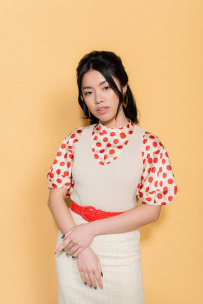Portrait of stylish asian model looking at camera on orange background - Foto, immagini