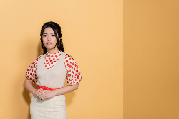 Pretty asian woman in vintage clothes on orange background - Foto, Imagen