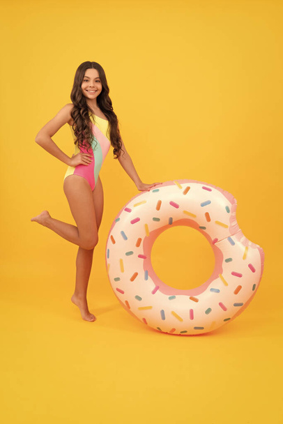 fröhliches Mädchen im Badeanzug aufblasbaren Donut-Ring. Teenager mit Schwimmring. - Foto, Bild