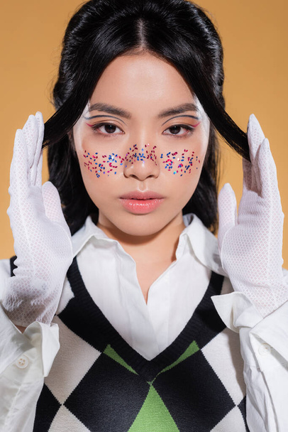 Portrait of asian model with makeup posing and looking at camera isolated on orange  - Photo, Image