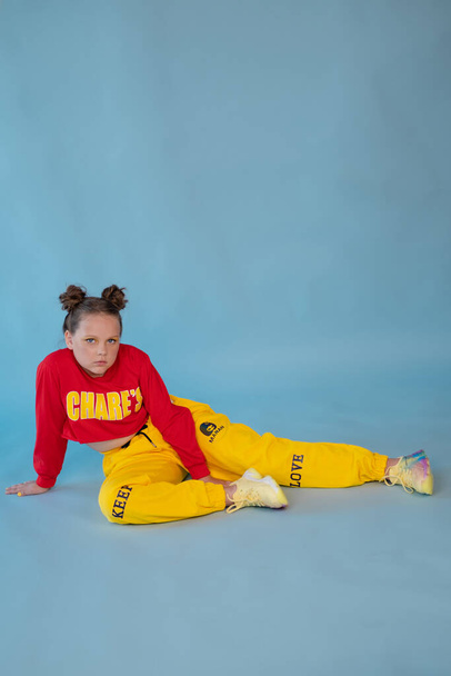 beauty portrait of stylish teenage girl in fashionable bright clothes. tween wearing red and yellow clothes on blue background. fashion portrait. two topknots. bright orange make up. - Fotó, kép