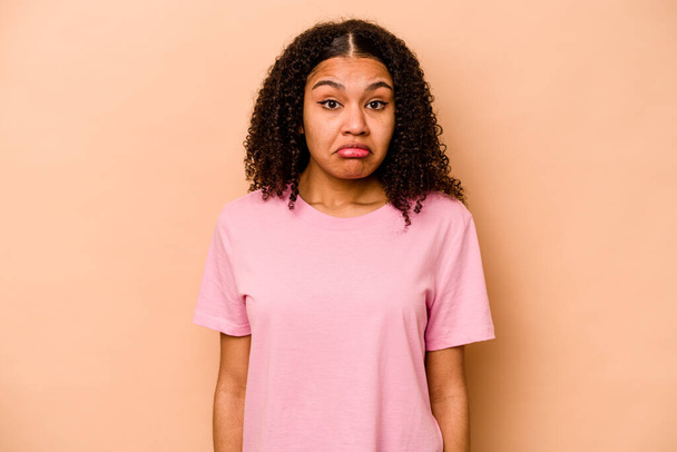Young African American woman isolated on beige background sad, serious face, feeling miserable and displeased. - Фото, изображение