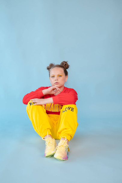 teenage girl in fashion stylish bright clothes. little lady in red and yellow on blue background. makeup and hairdo. - Foto, imagen