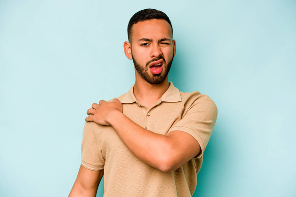 Young hispanic man isolated on blue background having a shoulder pain. - Fotoğraf, Görsel