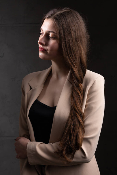 Portrait of a young brunette with long hair in the studio. Dramatic photo in dark colors. - Fotoğraf, Görsel