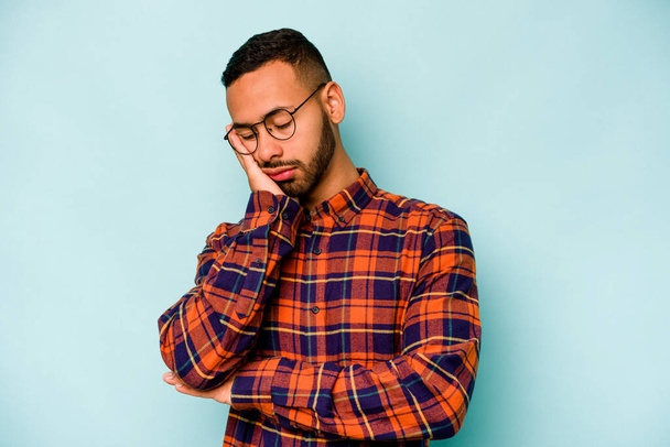 Young hispanic man isolated on blue background who is bored, fatigued and need a relax day. - Photo, image