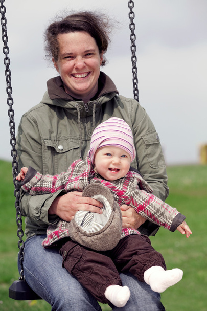 усміхнена дівчинка з мамою на гойдалці
 - Фото, зображення