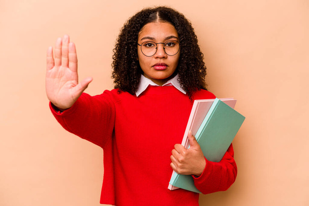 Young student African American woman isolated on beige background standing with outstretched hand showing stop sign, preventing you. - Photo, Image