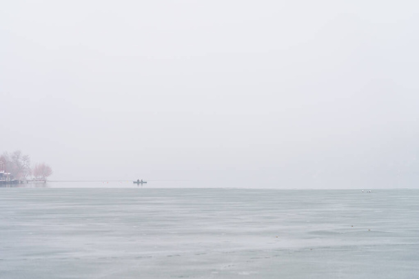 Egy folyó vagy víztározó ködös partja nedves hideg időben. Háttér másolási hellyel a szöveghez - Fotó, kép