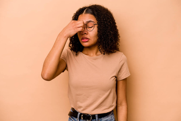 Fiatal afro-amerikai nő elszigetelt bézs háttér, amelynek fáj a feje, érintse meg az arc előtt. - Fotó, kép