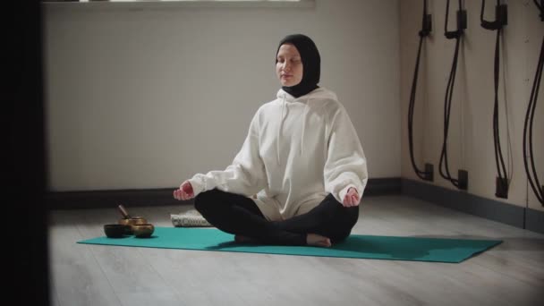 ヨガ-ヒジャーブの若い女性は瞑想のためにオブジェクトに囲まれたヨガをやって - 映像、動画