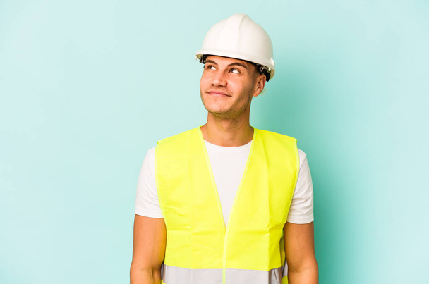 Young laborer caucasian man isolated on blue background dreaming of achieving goals and purposes - Photo, Image