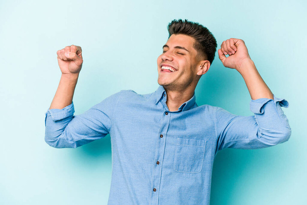 Young caucasian man isolated on blue background celebrating a special day, jumps and raise arms with energy. - Photo, Image