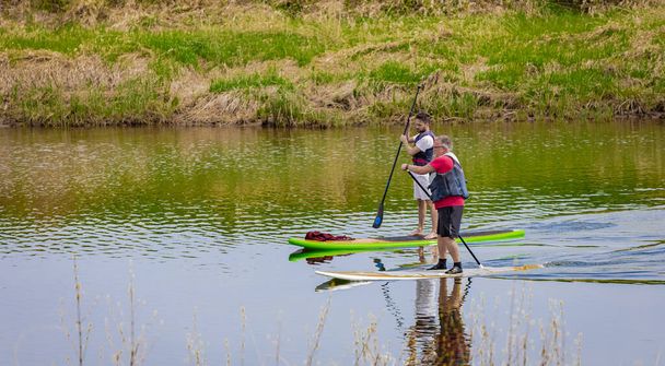 パドルボード楽しいSUPウォータースポーツの男性パドルボード上。夏の旅行はアクティブなライフスタイルに適しています- 4月24,2022-Whonnock Lake BC,カナダ.旅行写真、選択的焦点 - 写真・画像