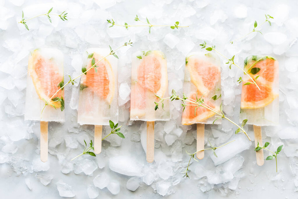 A row of beautiful grapefruit thyme popsicles on a bed of ice. - Photo, Image
