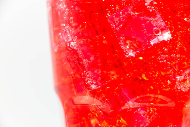 Red sparkling water with Ice in glass over white background.  - Фото, зображення