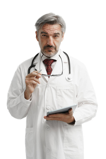 Portrait of confident Caucasian Medicare man in gown suit uniform with stethoscope and tablet stand over white background and looking toward to camera. - Valokuva, kuva