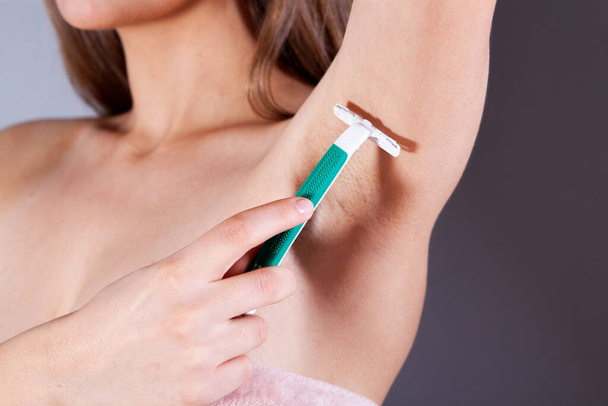 woman in bras shaves her armpit with a razor - Fotografie, Obrázek