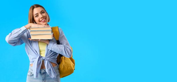 Female student holding books on light blue background with space for text - Foto, imagen