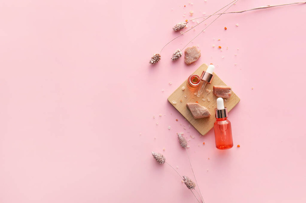 Flaschen mit natürlichem Serum, Salz und Blumen auf rosa Hintergrund - Foto, Bild