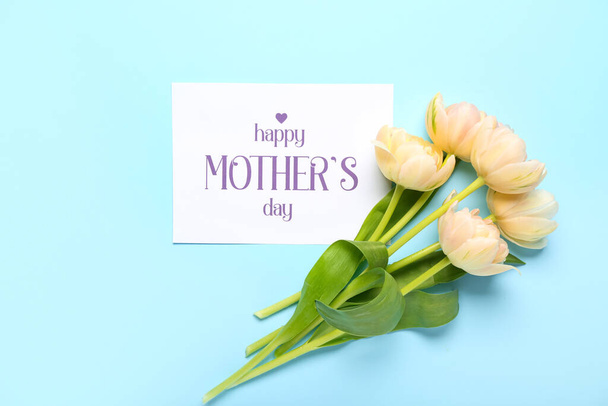 Kaart met tekst HAPPY MOTHER 'S DAY en bloemen op blauwe achtergrond - Foto, afbeelding