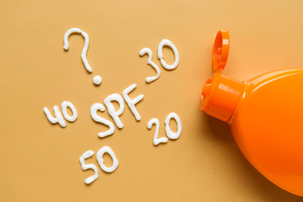 Ερώτηση SPF; και οι αριθμοί γίνονται με αντηλιακή κρέμα σε πορτοκαλί φόντο - Φωτογραφία, εικόνα
