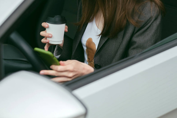 運転中に女がテキストメッセージを送りながら熱いコーヒーをこぼした。携帯電話の日常生活汚れた汚れ。高品質の写真 - 写真・画像
