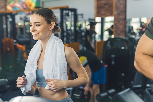 Portrait of attractive young athlete woman in the gym with a towel around her neck - Photo, Image