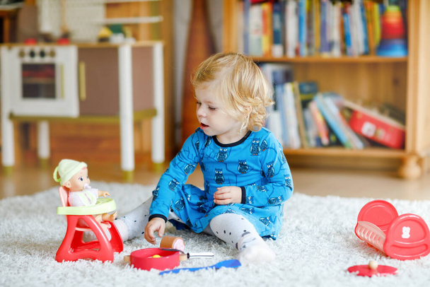 Adorable cute little toddler girl playing with doll. Happy healthy baby child having fun with role game, playing mother at home or nursery. Active daughter with toy. - Photo, Image