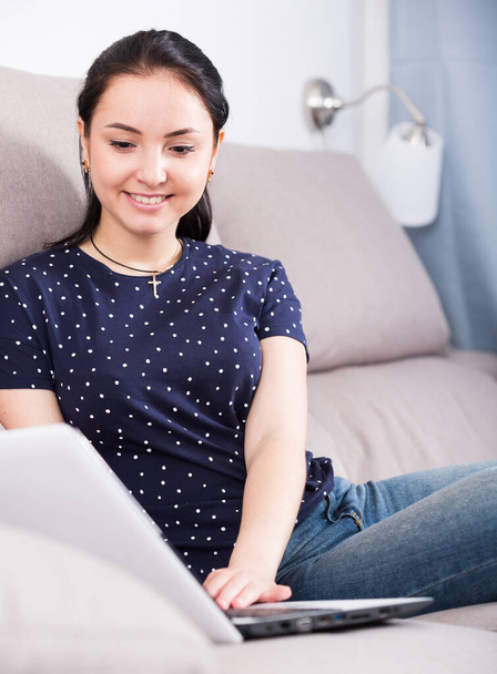 Smiling girl on sofa with laptop - 写真・画像