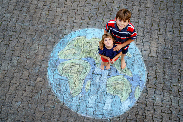 Niña preescolar y niño de la escuela con la pintura globo de tierra con tiza de colores en el suelo. Feliz concepto del día de la tierra. Creación de niños para salvar el mundo, el medio ambiente y la ecología. - Foto, Imagen