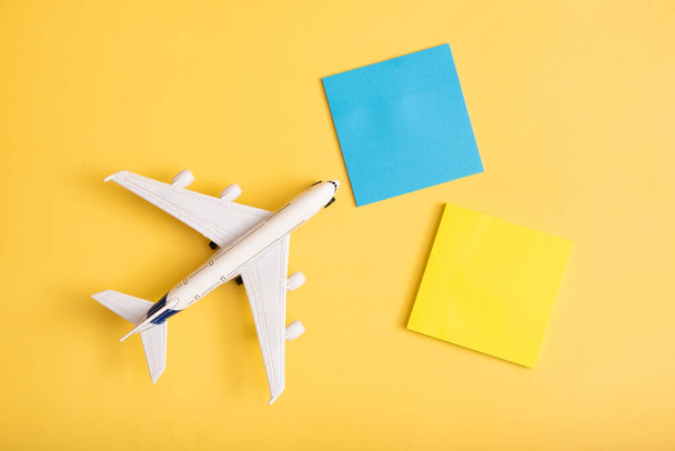 Composición plana de viaje en el avión de fondo amarillo con papeles de nota en blanco. Viaje preparar concepto. - Foto, imagen