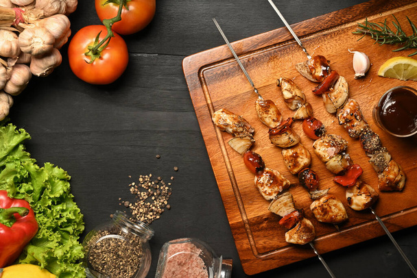 Homemade chicken shish kabobs with tomato, sweet pepper and onions on black wooden table - Photo, Image