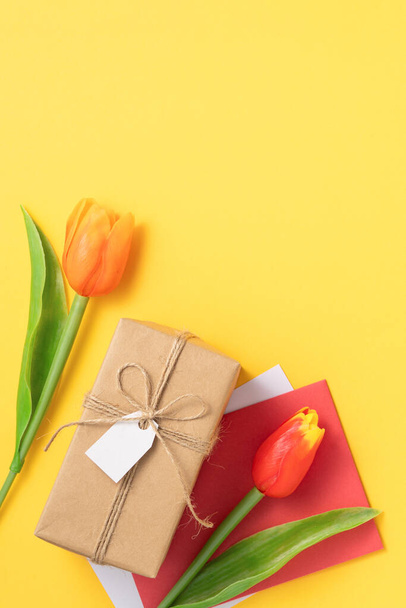Mother's day background concept. Top view design of holiday greeting gift with tulip bouquet on bright yellow table background - Foto, immagini