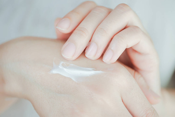 Hautcreme auf der Hand der Frau, um der Haut Feuchtigkeit zu verleihen. Konzept der Gesundheitsversorgung der Hand. - Foto, Bild