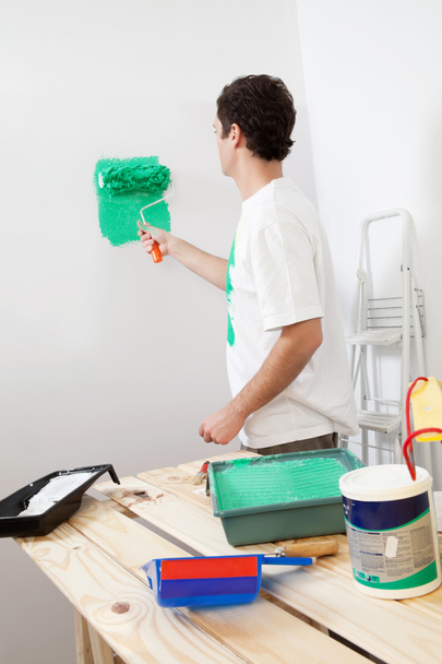 Casual man painting the wall of his new apartment - 写真・画像
