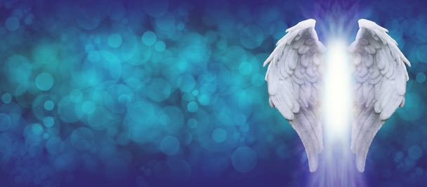 Angel Wings modrá bokeh široká zpráva pozadí - pár bílých andělských křídel na pravé straně tmavě modré absolvoval azurově modré pozadí bokeh s kopií prostoru na levé straně  - Fotografie, Obrázek